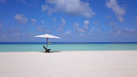 chair in shade under parasol in maldives on deserted sand bar, slow panning shot