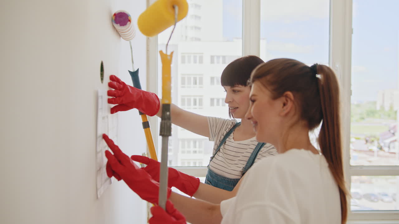 두 명의 여성이 벽을 칠하고 있습니다.