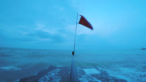 a dark red flag is flying on the edge of lake michigan pier