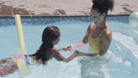 Happy-african-american-mother-and-daughter-having-swimming-lesson-in-swimming-pool,-slow-motion