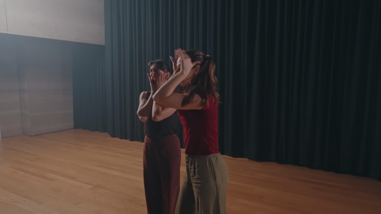 two women dancing contemporary choreography on wooden floor in studio