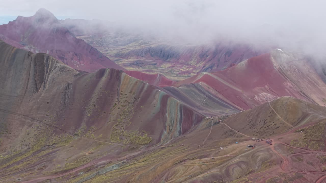 Drone in retromarcia sopra Vinicunca sotto nuvole basse, Perù.