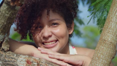 Facial-close-up-of-a-red-hair-light-skin-girl-in-a-park-with-leaves-of-a-tree-in-the-foreground