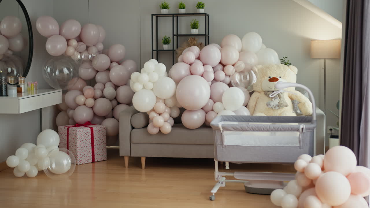 Delicati palloncini rosa e bianchi adornano la cameretta con culla e orsetto di peluche, creando un'atmosfera festosa per il neonato