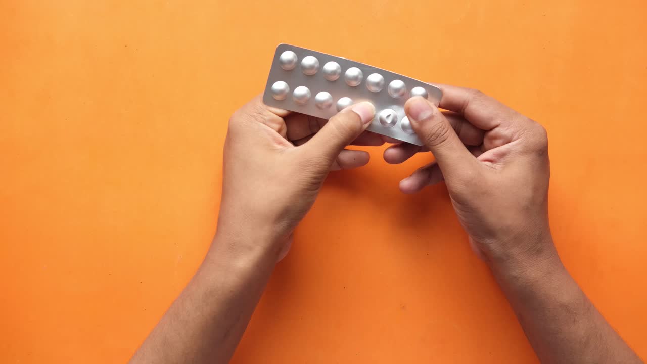 las manos tomando pastillas del envase de ampollas