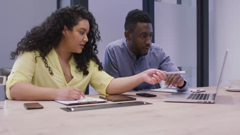 una pareja diversa de gente de negocios trabajando juntos, usando una computadora portátil en una oficina moderna