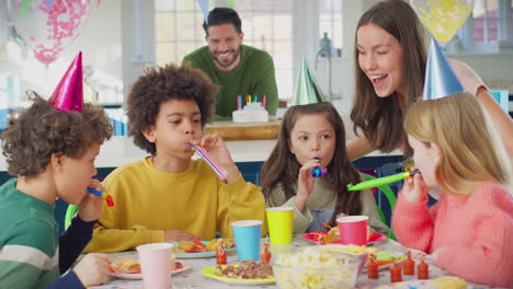 Girl-With-Parents-And-Friends-At-Home-Celebrating-Birthday-With-Party-And-Blowers