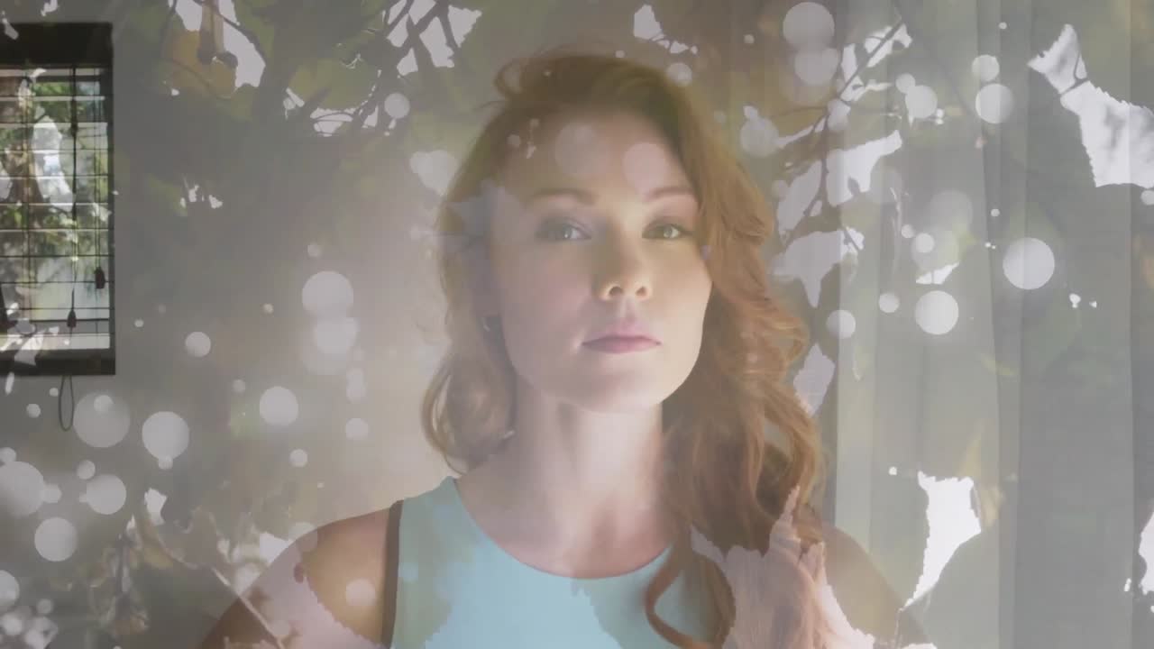 animación de manchas de luz y hojas sobre el retrato de una feliz mujer caucásica.