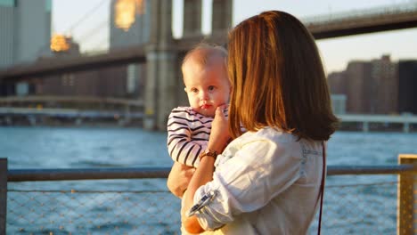 young mother with daughter standing by bridge, manhattan