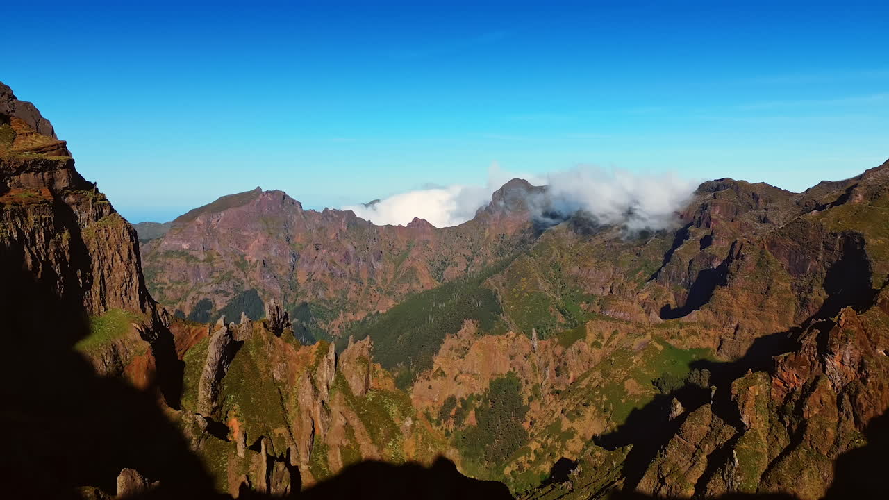 Thick white cloudscape approaches from behind the mountain top. Splendid scenery of the Madeira Islands, Portugal. Blue sky at backdrop.