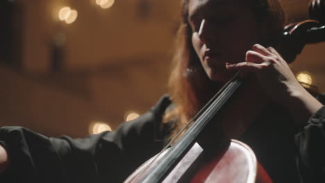 portrait of beautiful emotional female violoncellist on scene of opera house woman is playing cello