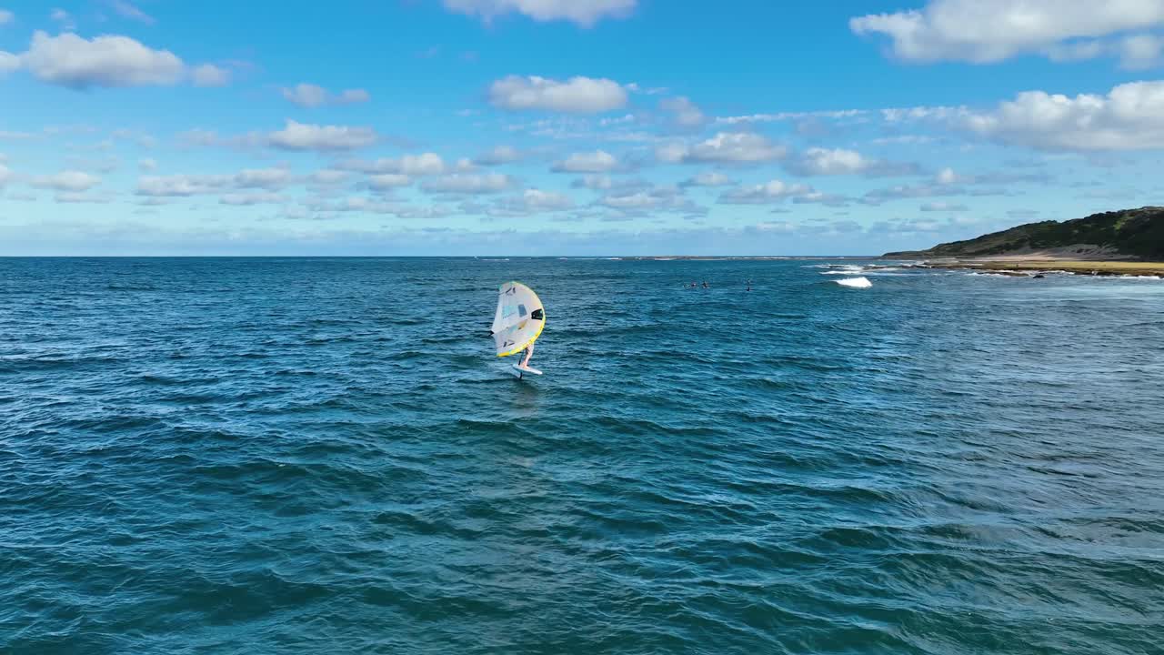 fotografía aérea de una persona montando hidrofoil y surfando en un hermoso día soleado en el océano