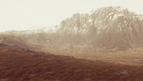 Plain-with-dried-grass-and-mountain-peaks-in-the-background