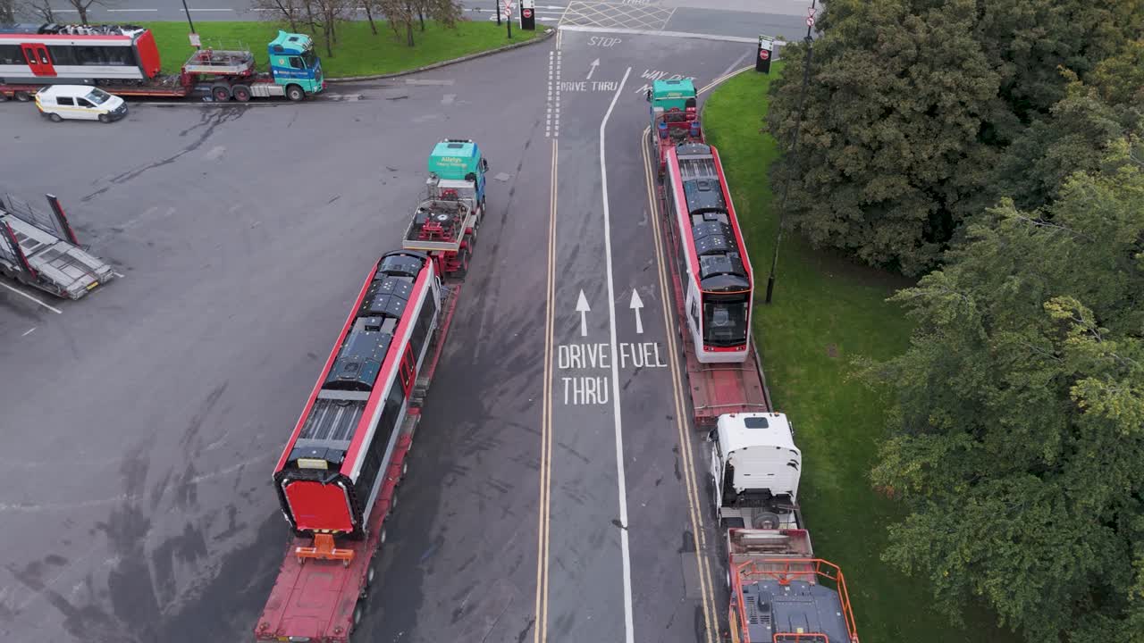 Aerial view of trams loaded onto lorries at Gordano Motorway Services, illustrating transportation and logistics, Bristol UK, October 2024