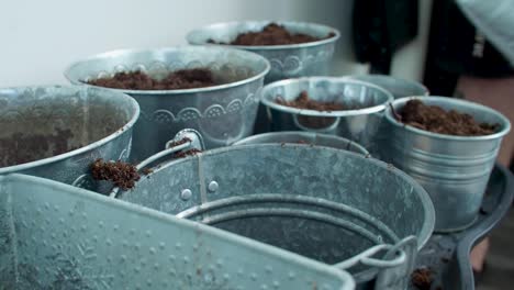 a masculine hand is pouring soil into the buckets, filling them up with the earthy material