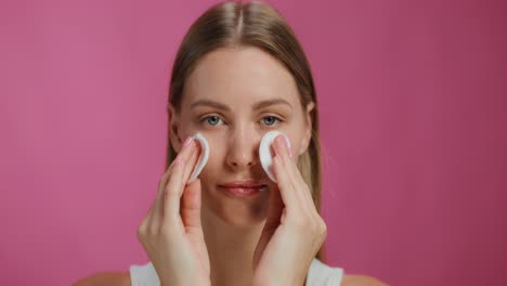 woman cleansing face with cotton pads