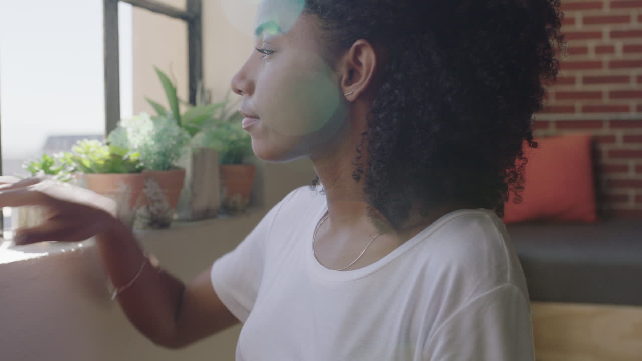 hermosa mujer afroamericana usando un teléfono inteligente en casa navegando por mensajes disfrutando de un estilo de vida relajado mirando por la ventana planeando hacia adelante mujer negra enviando mensajes de texto en el teléfono móvil
