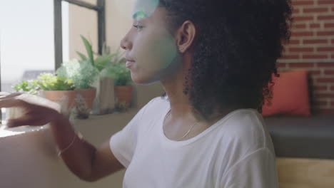 hermosa mujer afroamericana usando un teléfono inteligente en casa navegando por mensajes disfrutando de un estilo de vida relajado mirando por la ventana planeando hacia adelante mujer negra enviando mensajes de texto en el teléfono móvil