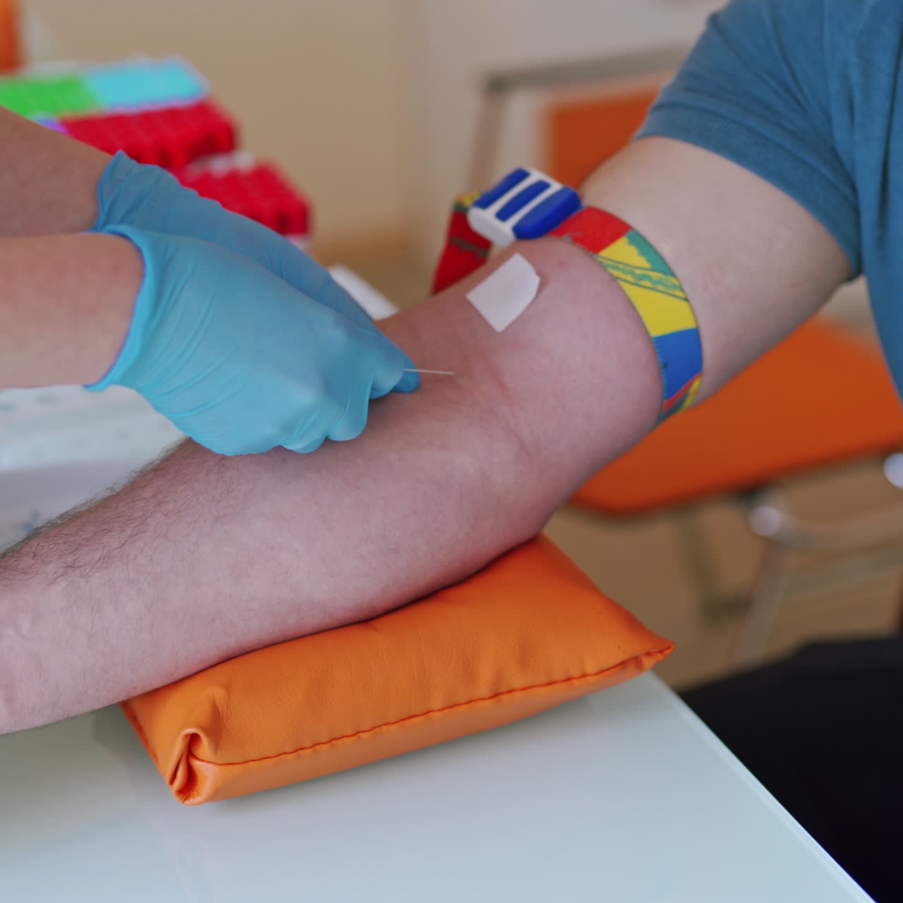 Female hands in blue gloves taking a blood sample for tests. Hand of doctor injects a syringe into a vein of a male patient. Close-up