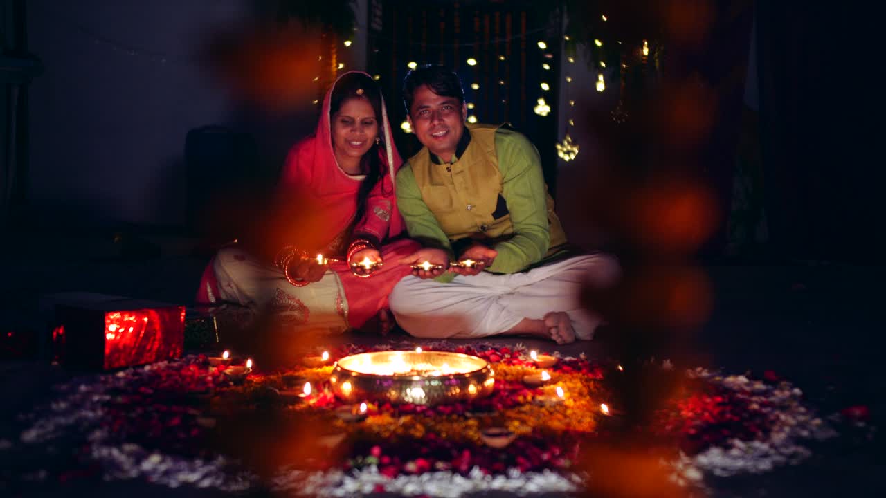 Pár slaví barevné diwali rangoli – červená, růžová, oranžová, zelená