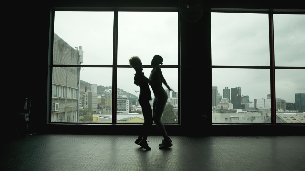 Silhouetted Dancers in Gym with City View