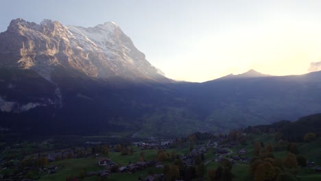 imágenes aéreas de drones dolly de izquierda a derecha, grindelwald village y eiger north face al atardecer en otoño
