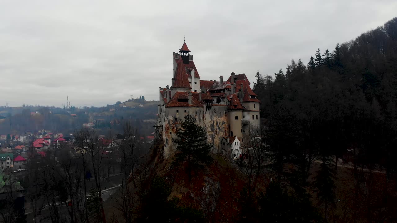 Aerial, rising, drone shot, tilting towards the Bran castle, home of the Dracula legend, on a foggy, overcast, fall day, in Transylvania, Romania