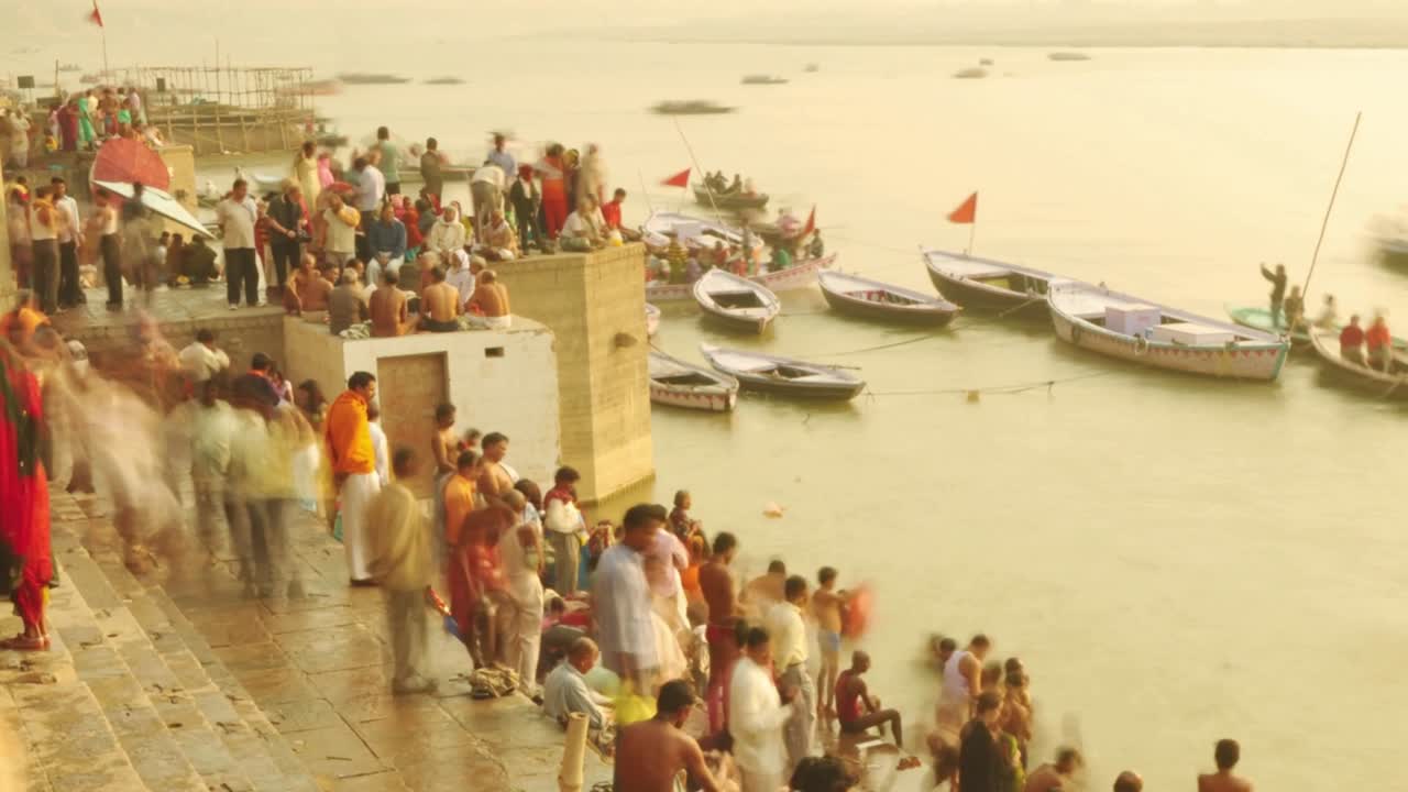 el lapso de tiempo de los peregrinos indios remando en un barco al amanecer. río ganges en varanasi, india.