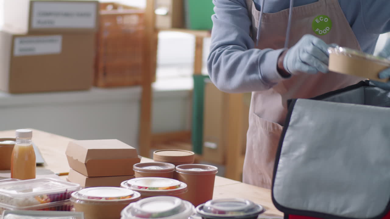 hombre afroamericano con máscara empaquetando pedidos de alimentos ecológicos para entrega