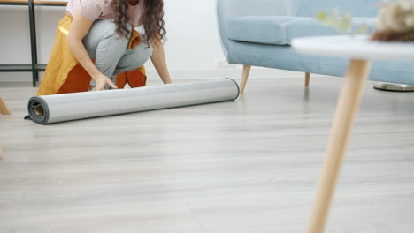 woman rolling out carpet in living room