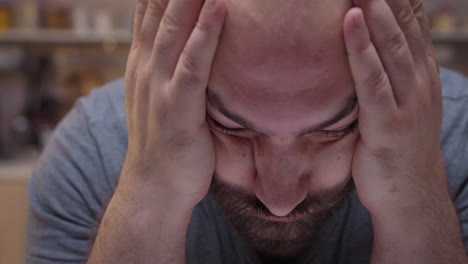 man with headaches sitting in the kitchen