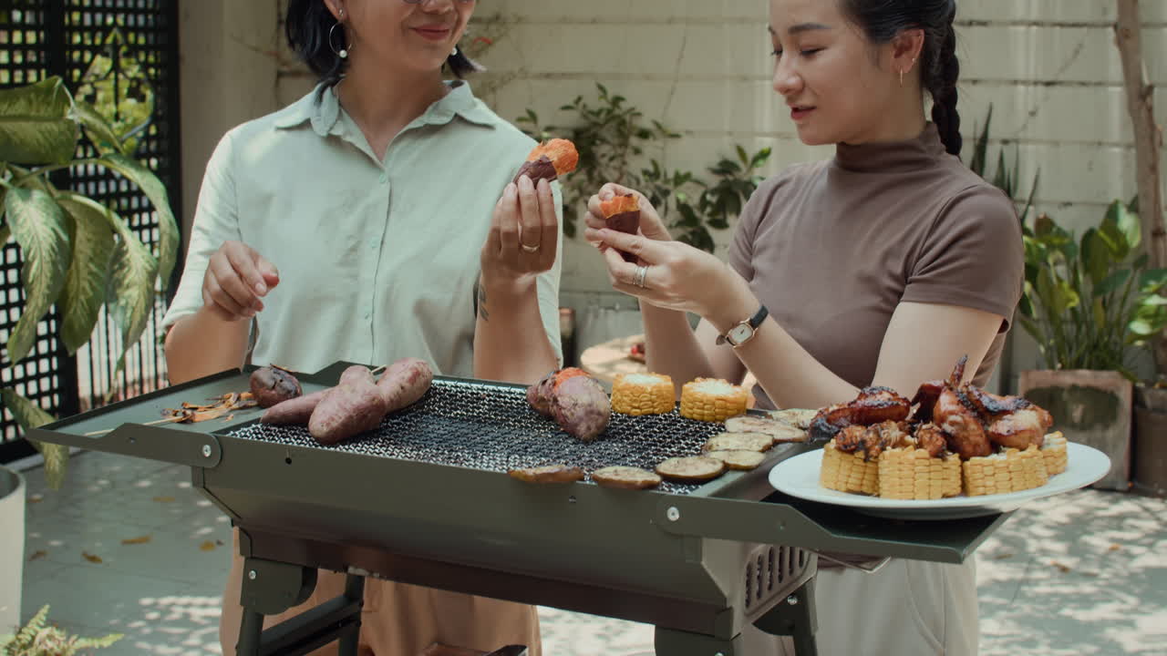 Two Women Peeling Sweet Potato during Barbecue Party