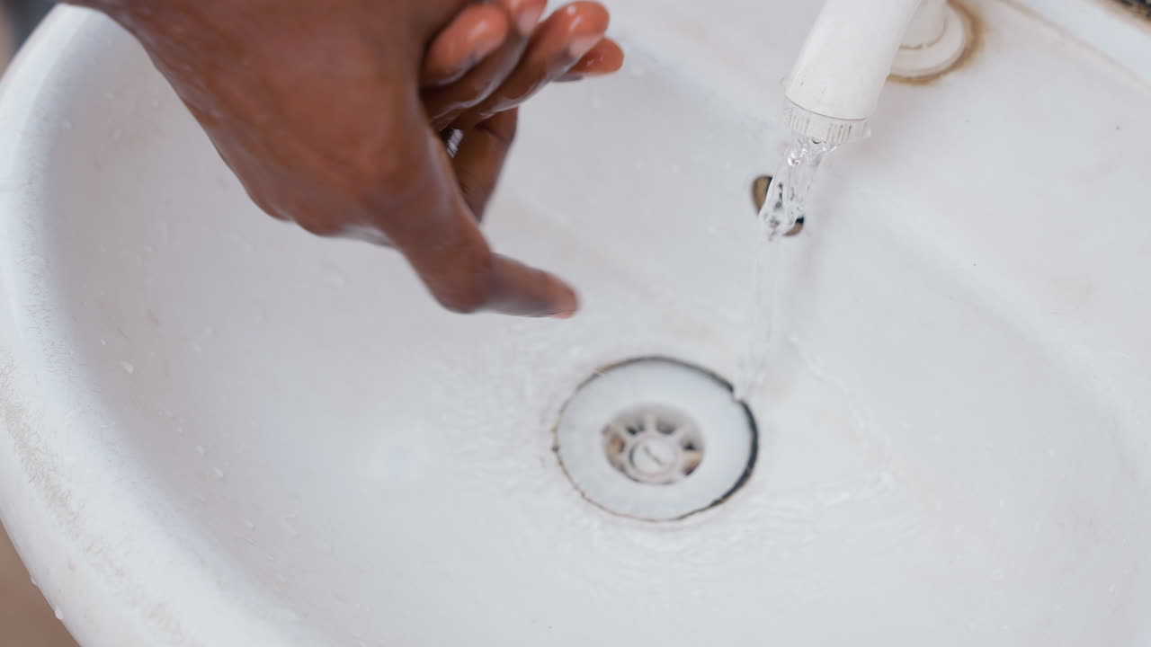 Resident performing routine hand washing. Individual engaged in peaceful home hand cleansing activity. Person maintaining hygiene through daily hand washing in calm domestic setting