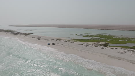 remote beach on masirah island with two cars and peaceful ocean and lagoon view