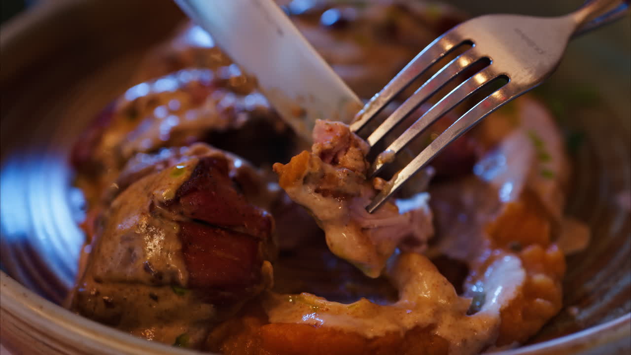 Close up of meat being cut over a bed of a sweet potato puree at a restaurant