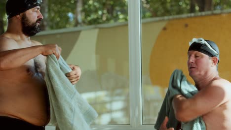 Two men drying themselves with towels after swimming
