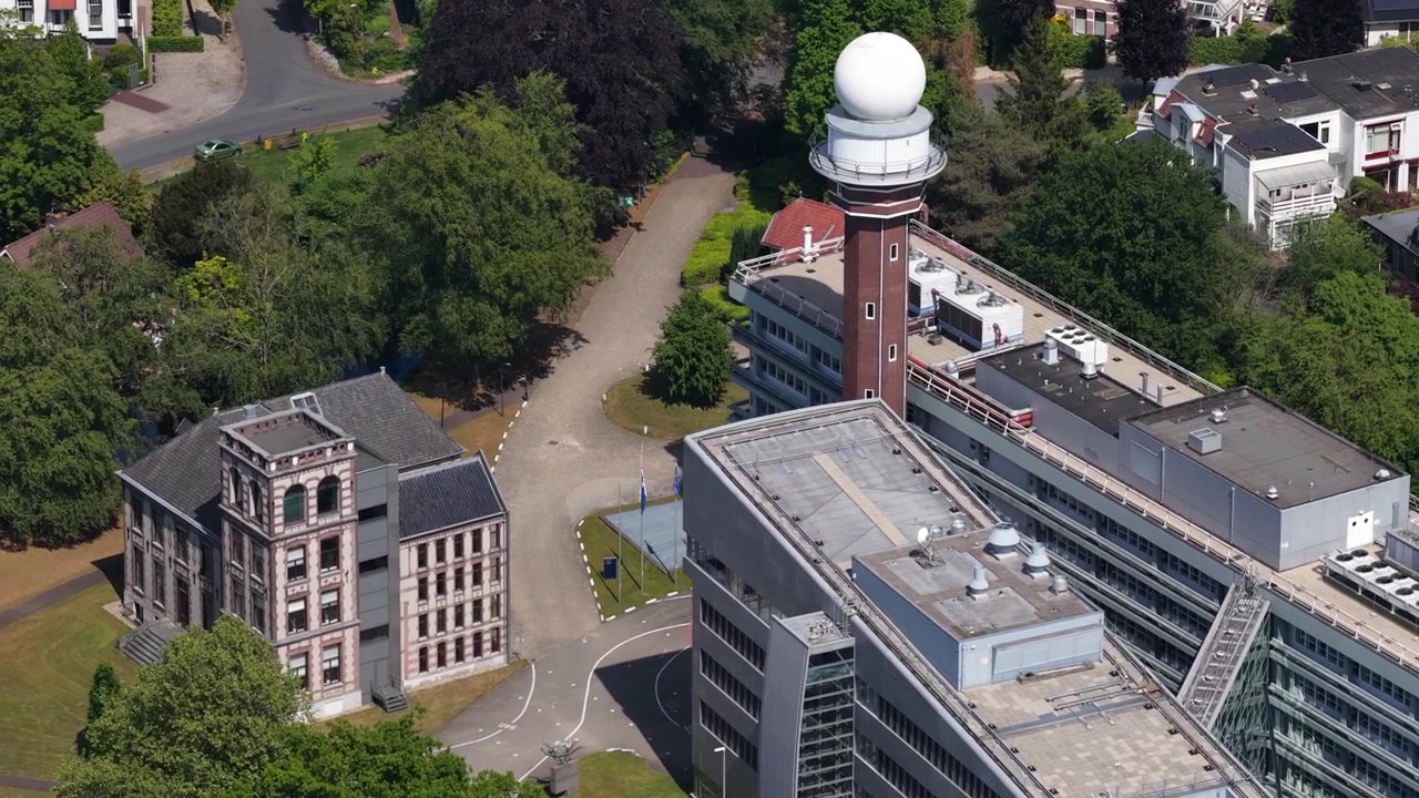 Veduta aerea dall'alto del campus dell'Istituto meteorologico reale olandese, KNMI, a De Bilt, che mostra l'iconica torre radar meteorologica e gli edifici per uffici moderni e classici circostanti.