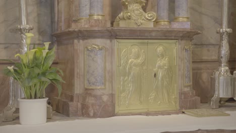 a crucifix stands above a tabernacle in a baroque altar, two candlesticks and flowers