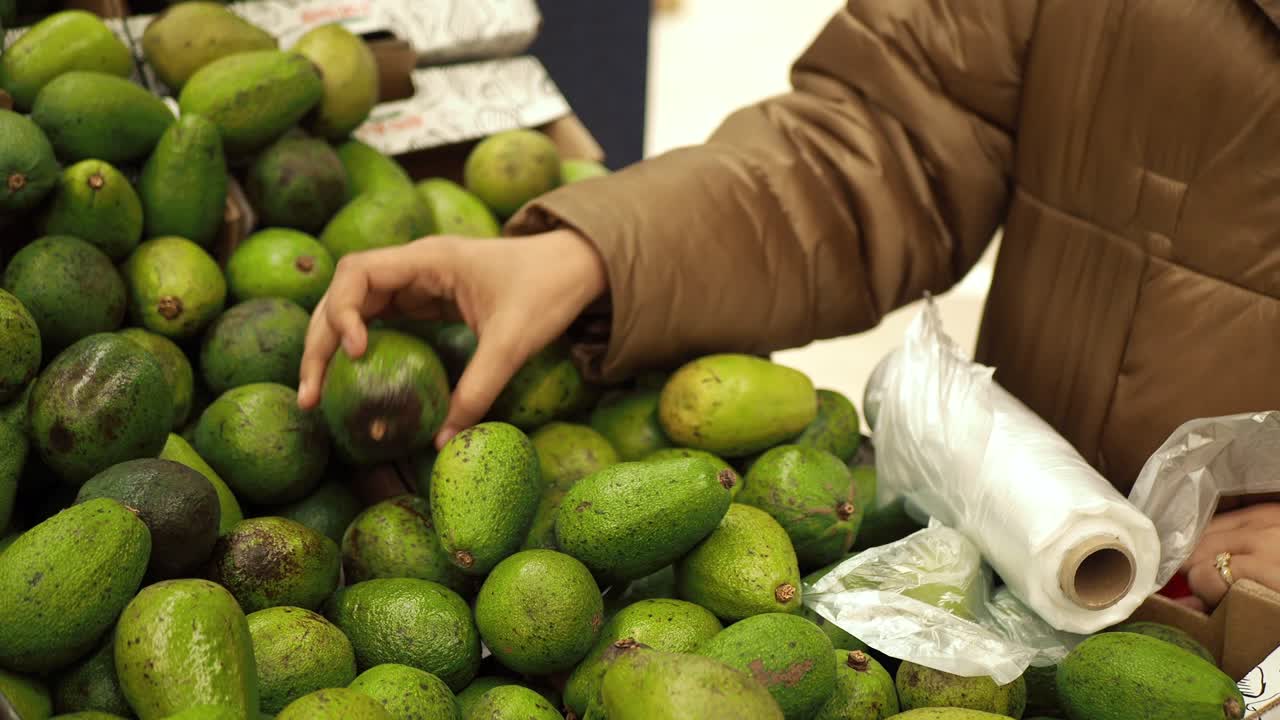 persona seleccionando aguacates en una tienda de comestibles