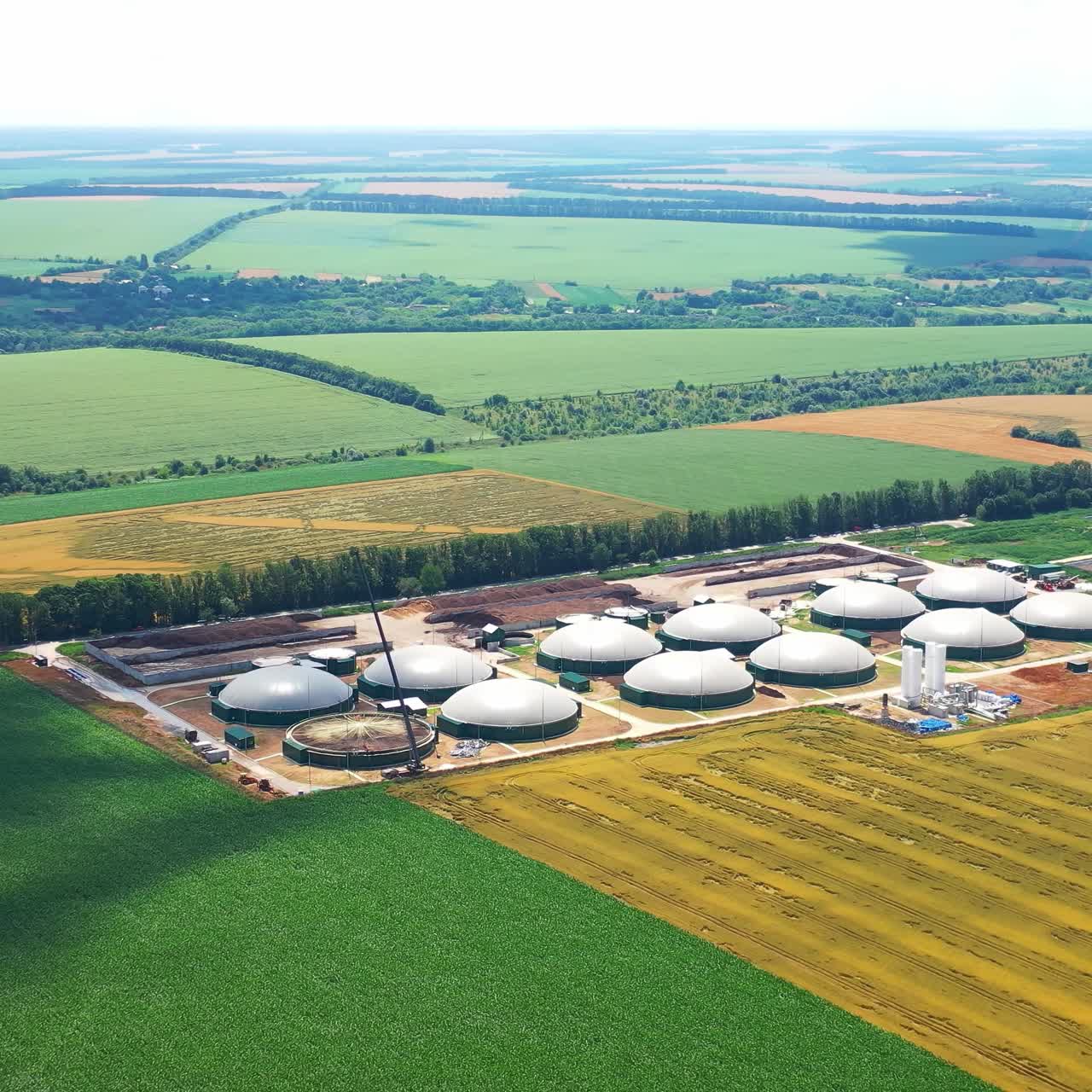 Biogas complex on field in summer. Enterprise for processing organic waste. Organic plant for biogas technologies. Aerial view