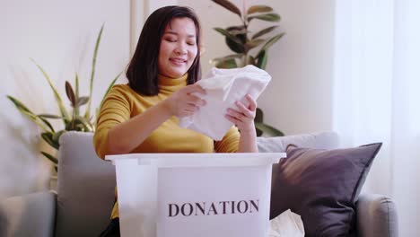 woman selecting clothes for donation and putting in box