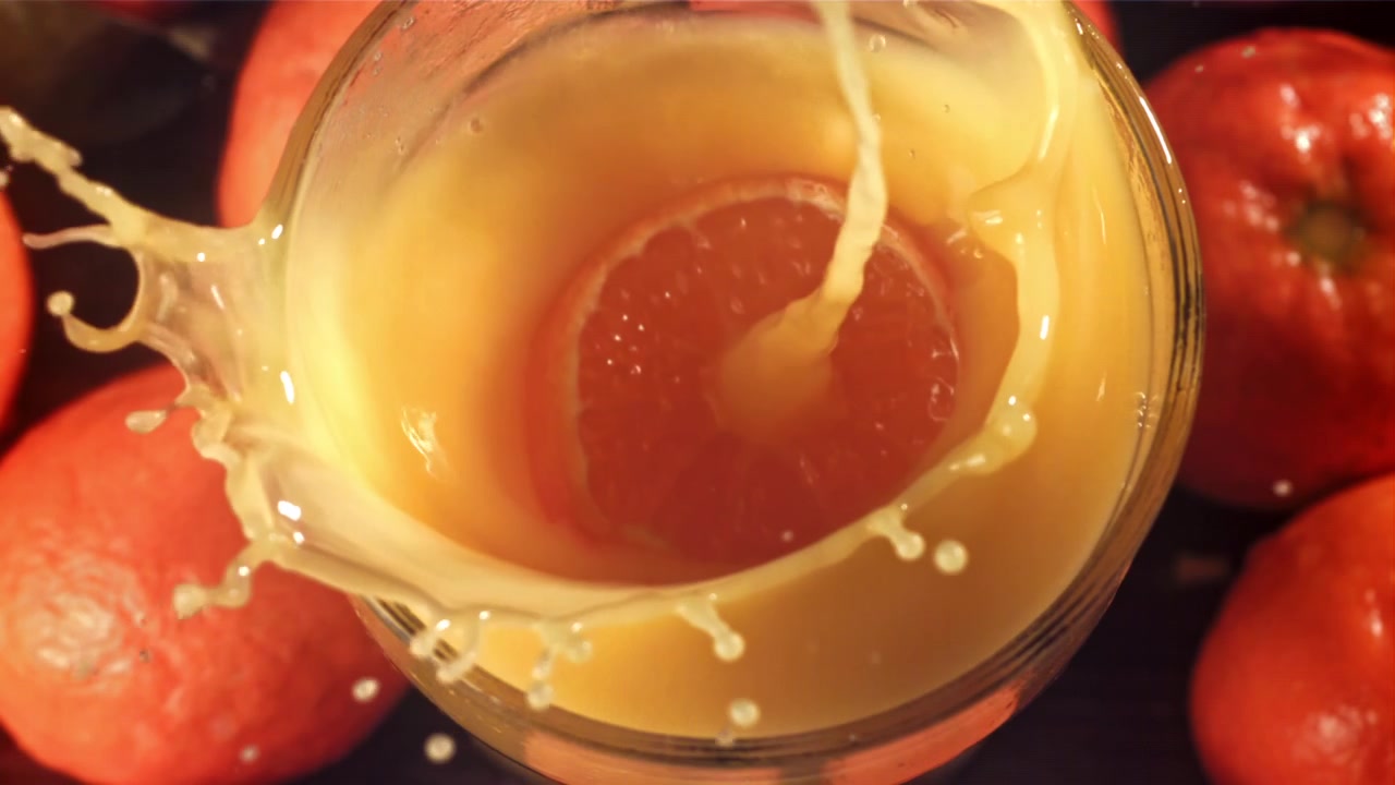 Fetta d'arancia che cade in succo d'arancia fresco con uno schizzo.