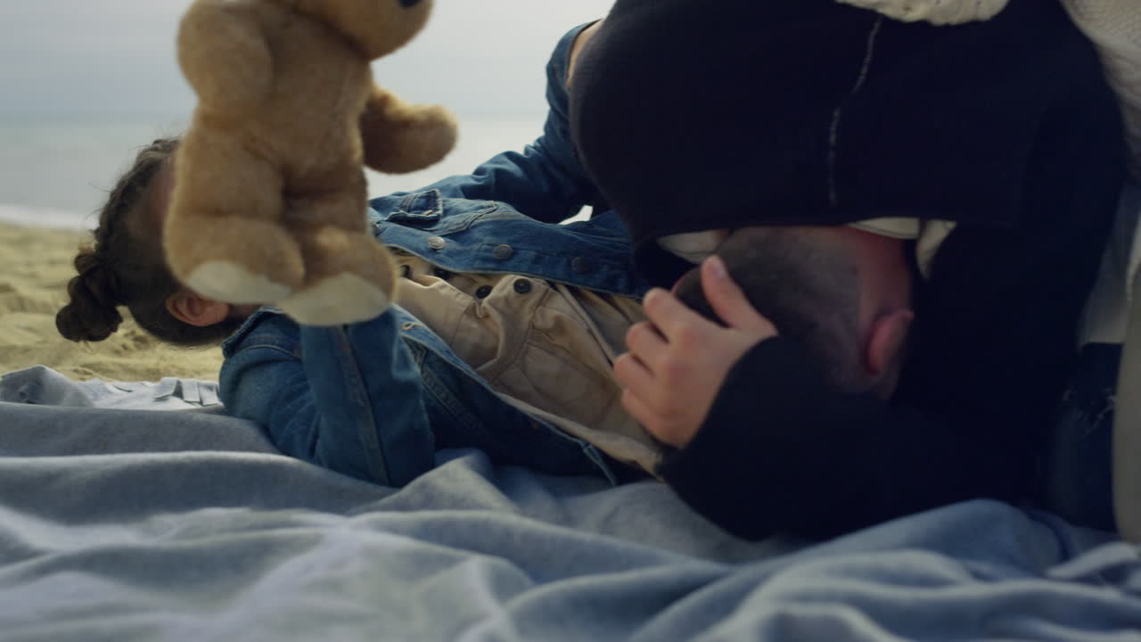 작은 아이가 바 ⁇ 가에서 부모와 놀고 가족이 바 ⁇ 가에서 함께 시간을 보내고 있습니다.