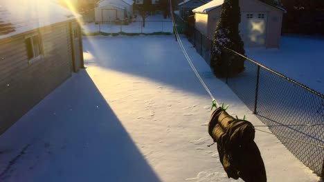 wide time lapse of sun setting from light to dark, throwing a moving shadow on a snowy backyard, with jacket hanging on a laundry line, swinging wildly in the high winds