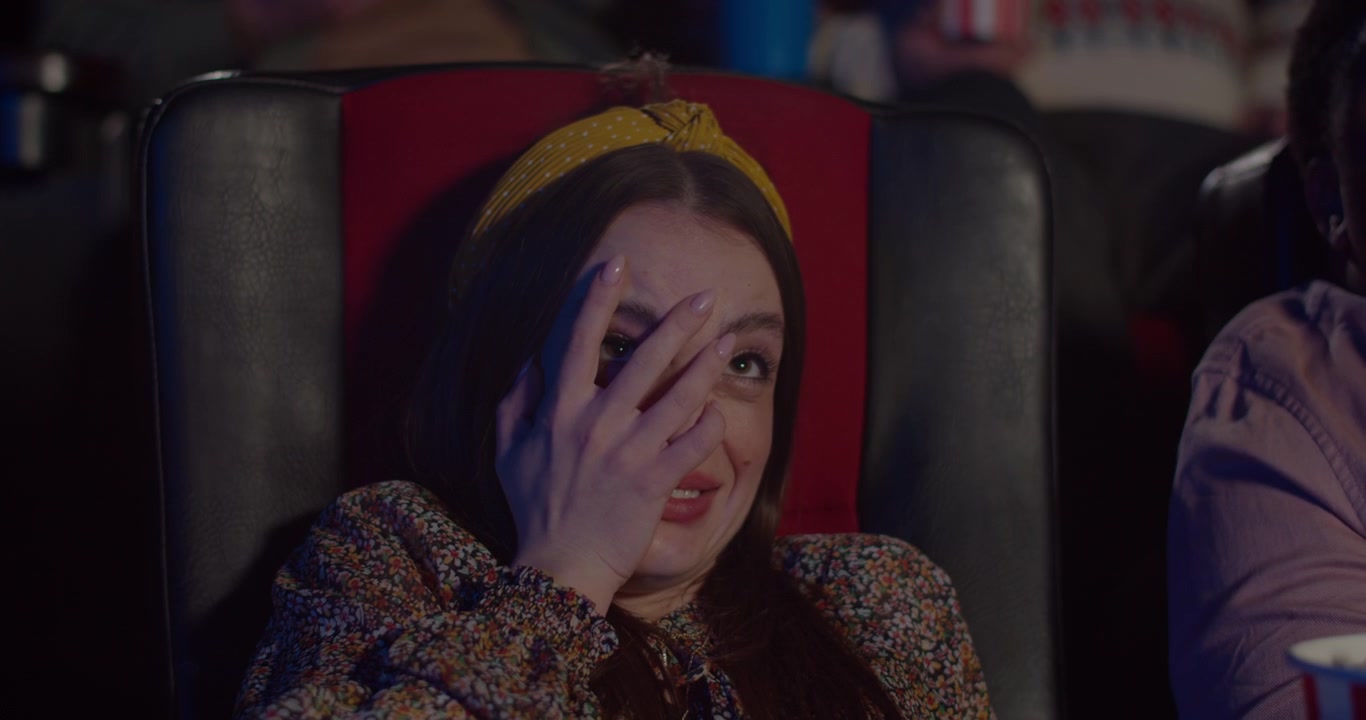 Jeune femme regardant un film d'horreur dans un cinéma