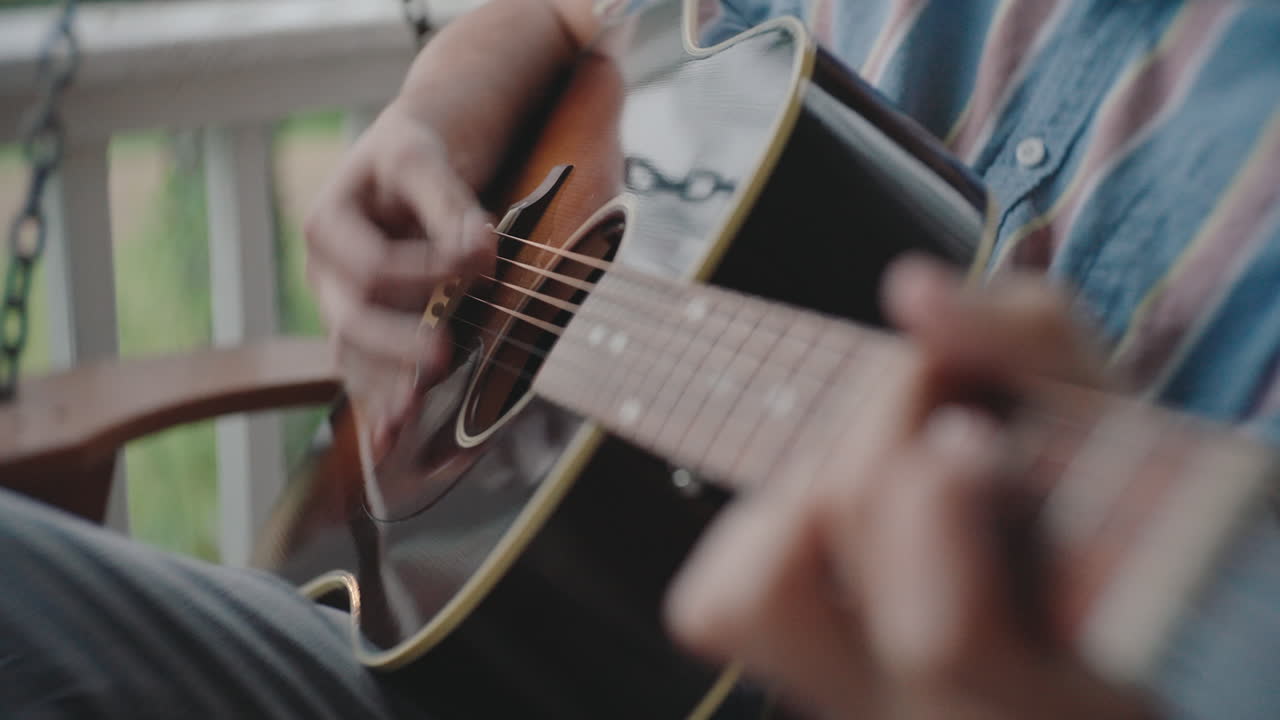 Man playing acoustic guitar on a porch