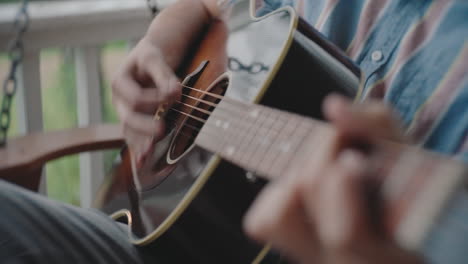 man playing acoustic guitar on a porch