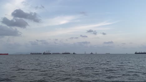 Anchored cargo ship in the Arabian Sea near Mumbai, with smaller boats nearby.