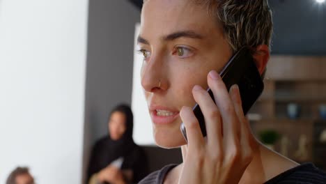 Executive-talking-on-mobile-phone-while-colleague-discussing-in-background-4k