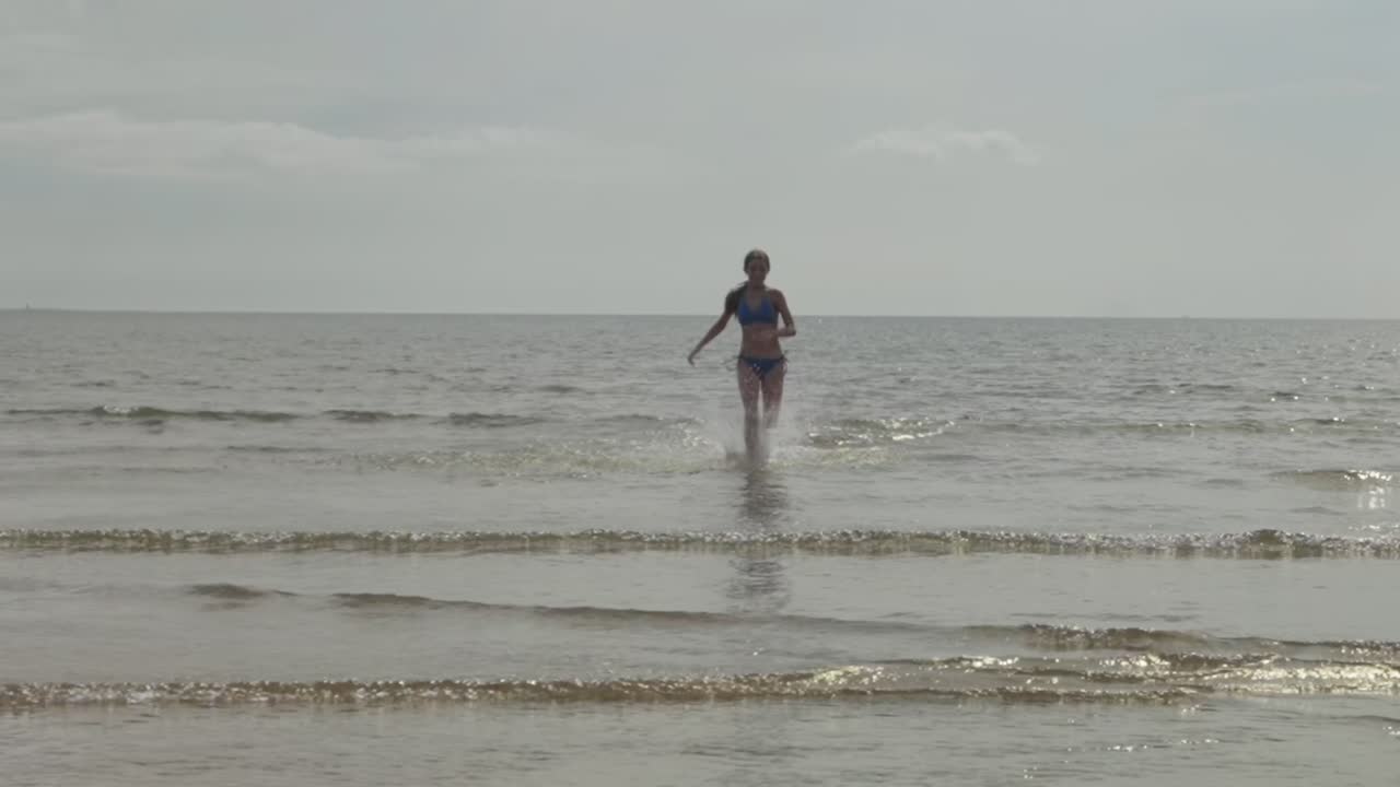 chica adolescente corriendo rápido, bikini, agua del océano, luz del sol, cámara lenta